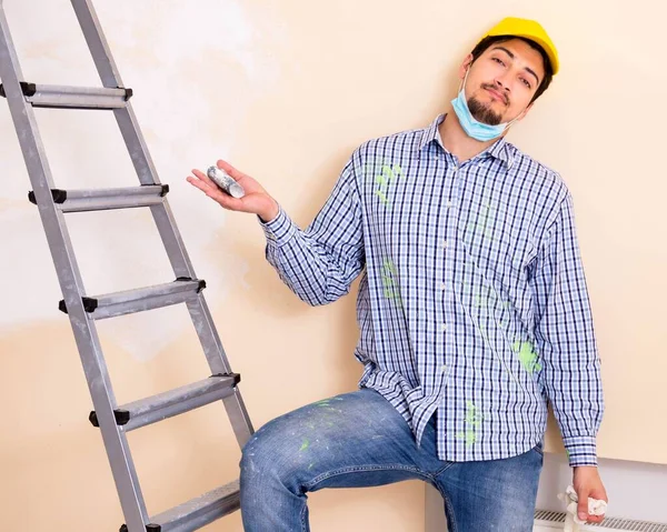 Contratista joven lijando pared con papel de lija — Foto de Stock