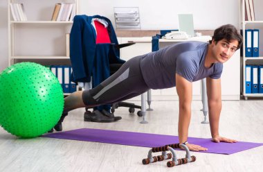 Ofiste egzersiz yapan genç bir erkek.