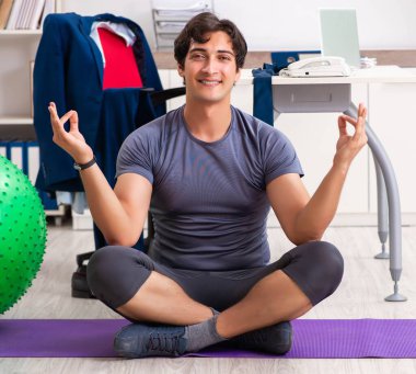 Ofiste egzersiz yapan genç bir erkek.