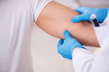 Genç adam deneyimli doktor dermatoloğu ziyaret ediyor.