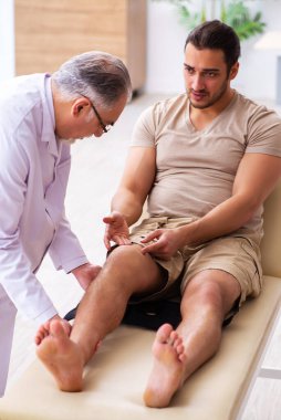 Deneyimli doktor travmatolog genç erkek hastayı muayene ediyor.