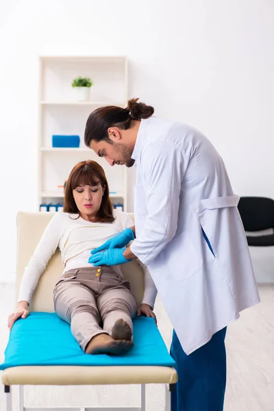 Injured young woman visiting young male doctor — Stock Photo, Image