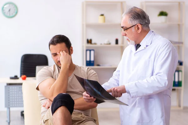 Experienced doctor radiologist examining young male patient — Stock Photo, Image
