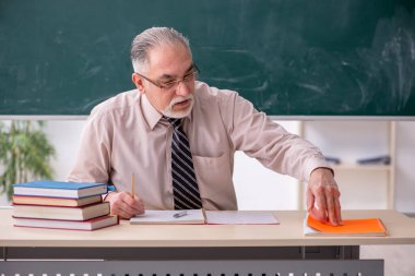 Sınıftaki yaşlı erkek öğretmen.