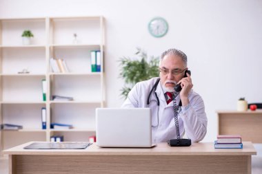 Klinikte çalışan yaşlı erkek doktor.