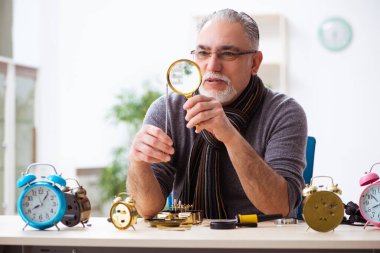 Atölyede çalışan yaşlı bir erkek saatçi.