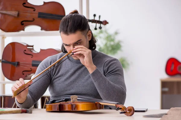 Young male repairman repairing violin