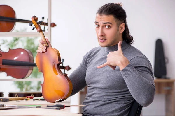 Young male repairman repairing violin