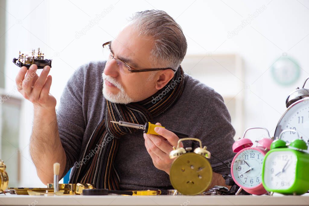 Old male watchmaker working in the workshop