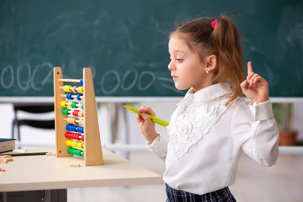Menina pequena na frente do quadro-negro na sala de aula — Fotografia de Stock