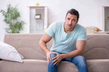 Evde acı çeken yaralı genç adam.