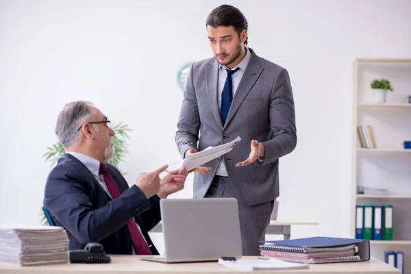 Velho chefe e seu jovem assistente trabalhando no escritório — Fotografia de Stock