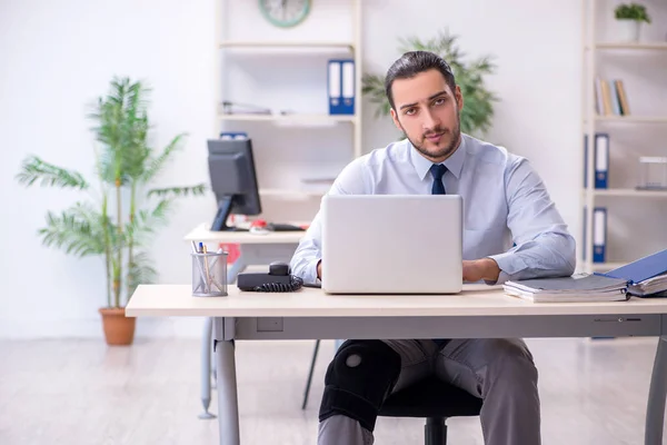 Junger Mitarbeiter bei Büroarbeit am Bein verletzt — Stockfoto