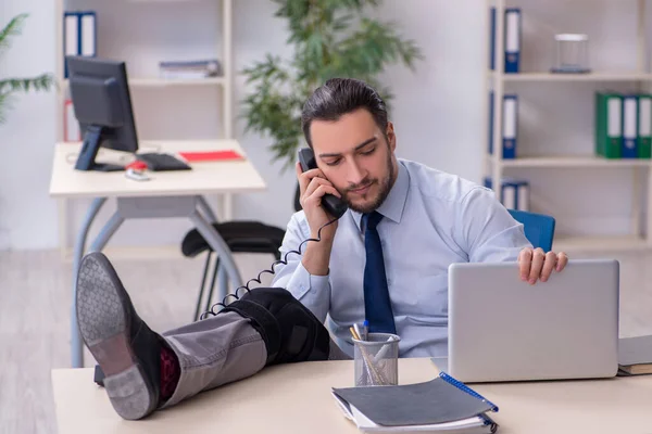 Junger Mitarbeiter bei Büroarbeit am Bein verletzt — Stockfoto