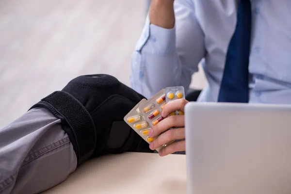 Young leg injured employee working in the office — Stock Photo, Image