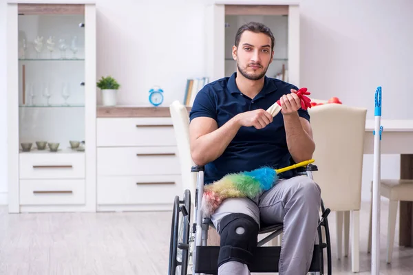 Jovem perna ferida empreiteiro em cadeira de rodas limpeza da casa — Fotografia de Stock