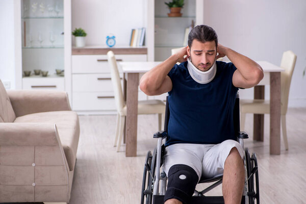 Young leg injured man in wheel-chair suffering at home