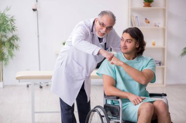 Tekerlekli sandalyedeki genç erkek hasta ve deneyimli doktor travmatolog.