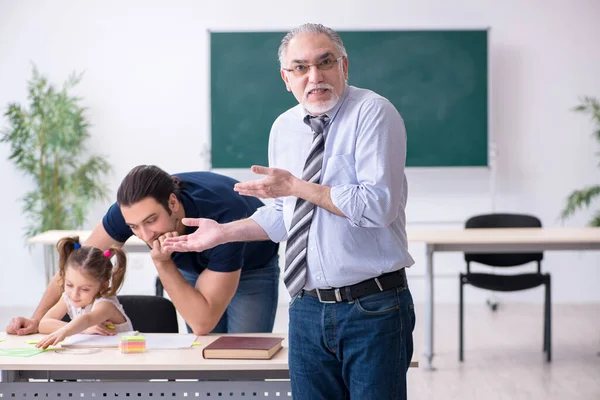 Jonge ouder, oude mannelijke leraar en klein meisje in de klas — Stockfoto