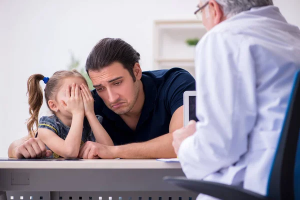 Joven padre y su hija visitando viejo médico masculino — Foto de Stock