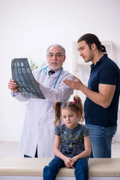 Jeune père et sa fille visitant vieux médecin masculin — Photo