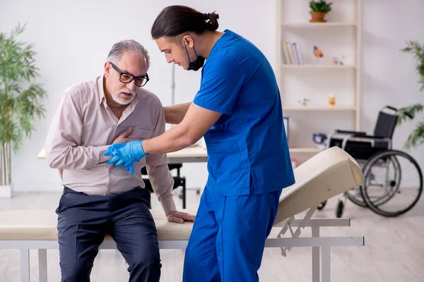 Yaşlı hasta genç erkek doktoru ziyaret ediyor.