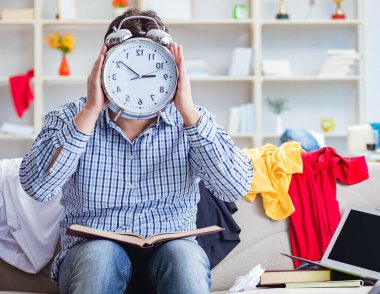 Dağınık odada çalışan genç adam.