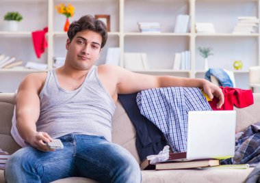 Dağınık odada çalışan genç adam.