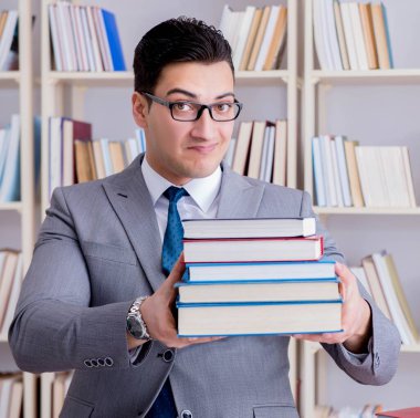 Kütüphanede kitap yığınıyla çalışan işletme hukuku öğrencisi.