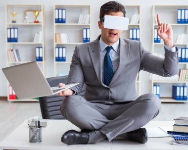Sanal gerçeklikteki iş adamı VR gözlükleri masanın üstünde meditasyon yapıyor.
