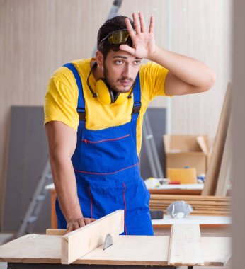 Genç tamirci marangoz daireler çizerek odun kesiyor.