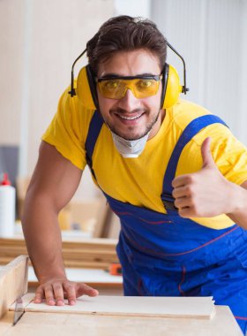 Genç tamirci marangoz daireler çizerek odun kesiyor.