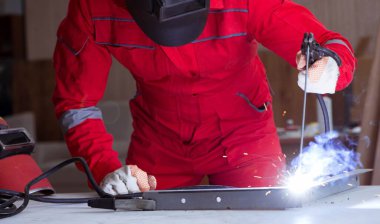 Kaynak tabancası elektrot ve kask takan genç bir tamirci.