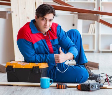 Genç marangoz ahşap kalaslarla çalışmaya ara veriyor.