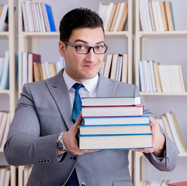 Kütüphanede kitap yığınıyla çalışan işletme hukuku öğrencisi.