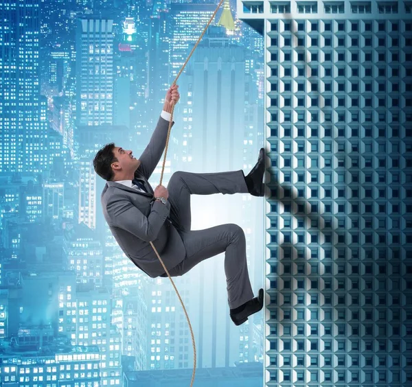 O empresário escalando arranha-céus no conceito de desafio — Fotografia de Stock