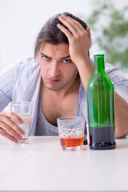 Genç erkek alkolik evde viski içiyor.