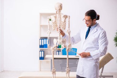 İskeleti olan genç erkek doktor.