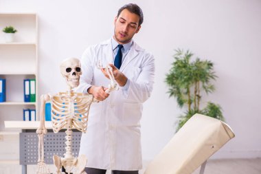 İskeleti olan genç erkek doktor.