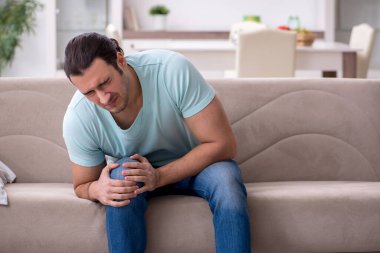 Evde acı çeken yaralı genç adam.