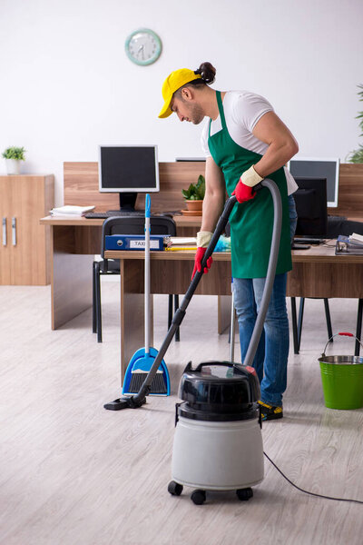 Young male contractor cleaning the office