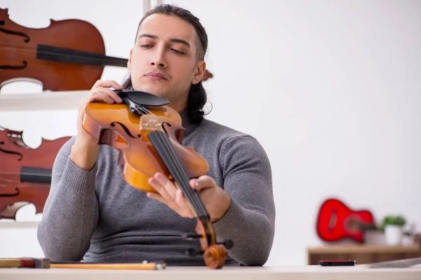 Young male repairman repairing violin