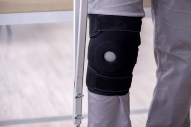 Koltuk değnekleriyle yaralı genç bir adam.