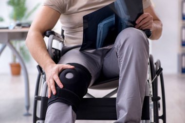 Tekerlekli sandalyedeki yaralı genç adam röntgene bakıyor.