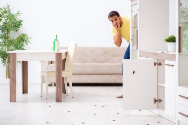 Genç adam ve evde bir sürü hamamböceği var.