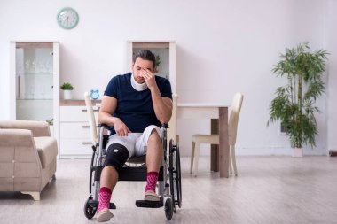 Evde acı çeken tekerlekli sandalyedeki yaralı genç adam.