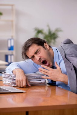 Genç erkek çalışan ofiste uyuyor.