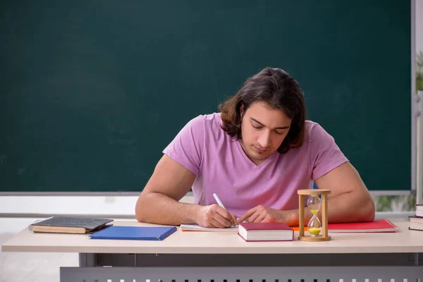 Joven estudiante masculino en el aula en el concepto de gestión del tiempo — Foto de Stock