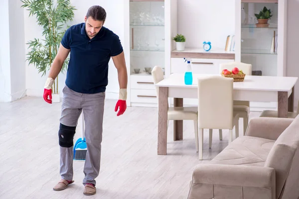 Young leg injured contractor cleaning the house — Stock Photo, Image
