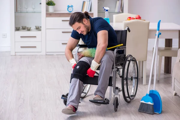 Young leg injured contractor in wheel-chair cleaning the house — Stock Photo, Image